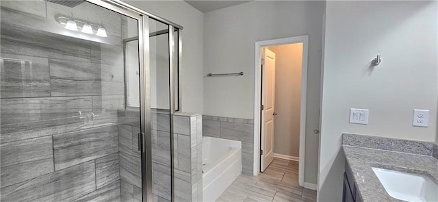 bathroom featuring a bath, vanity, baseboards, and a shower stall