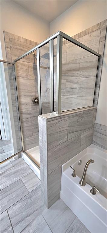 bathroom with tile patterned floors, a bath, and a stall shower