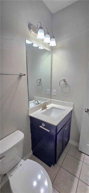 bathroom with toilet, baseboards, tile patterned flooring, and vanity