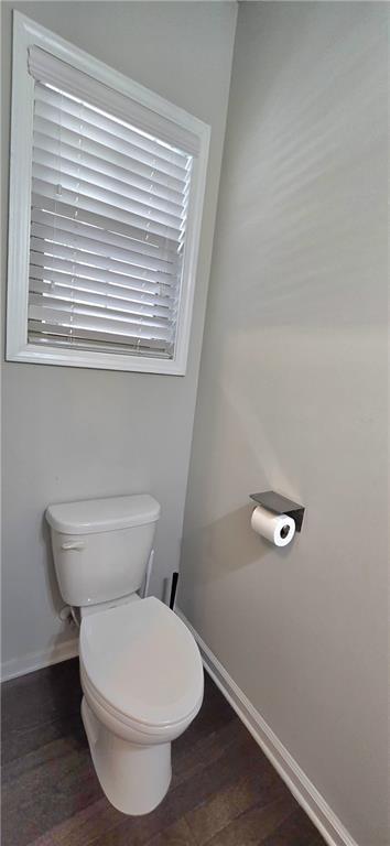 bathroom with toilet, baseboards, and wood finished floors