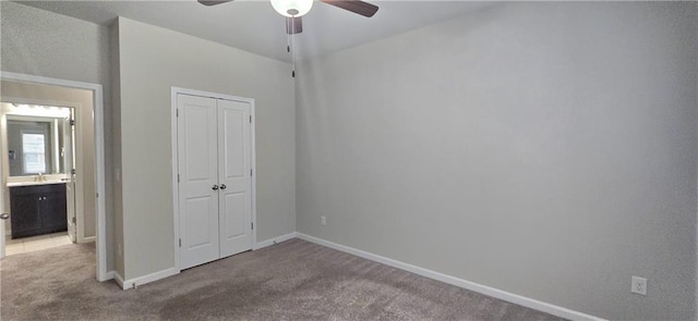 unfurnished bedroom with baseboards, carpet flooring, a closet, and a ceiling fan