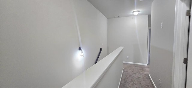 hall with carpet, baseboards, and an upstairs landing