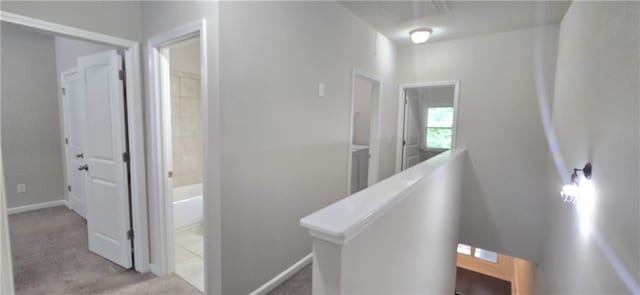 corridor featuring carpet floors, baseboards, and an upstairs landing