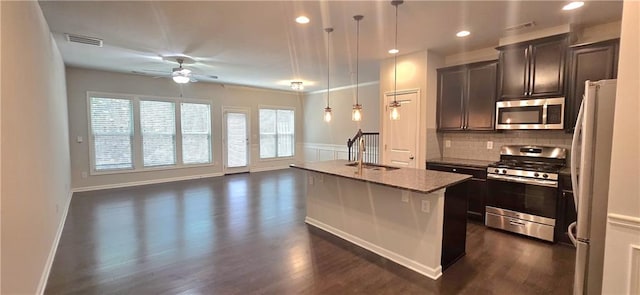 kitchen with stainless steel appliances, an island with sink, open floor plan, dark wood-style floors, and a ceiling fan