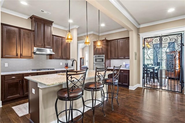 105 Laurel Canyon Trl, Canton, GA 30114 - kitchen with under cabinet range hood, a kitchen bar, dark wood-style flooring, a kitchen island with sink, and dark brown cabinetry