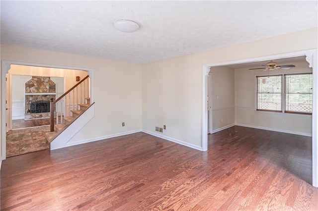 spare room featuring a fireplace, ceiling fan, a textured ceiling, and dark hardwood / wood-style floors