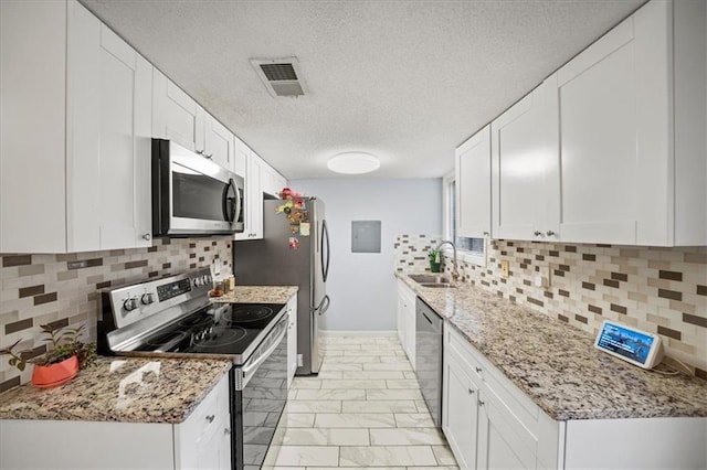 kitchen with backsplash, light stone counters, stainless steel appliances, sink, and white cabinetry