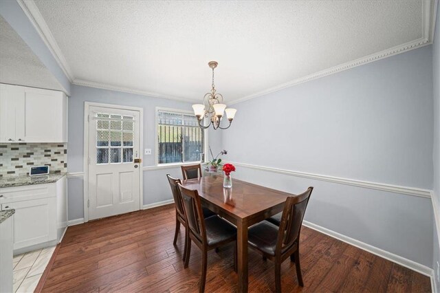 dining room featuring ornamental molding, dark wood-type flooring, and an inviting chandelier