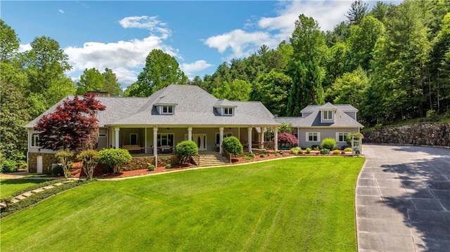 new england style home featuring covered porch and a front lawn