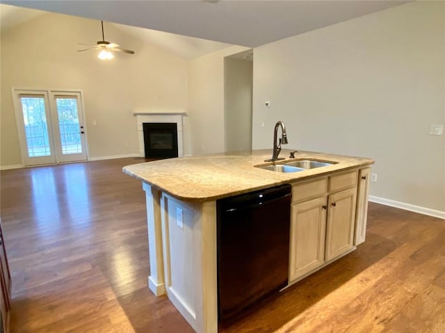 kitchen featuring dark wood-type flooring, a kitchen island with sink, a sink, black dishwasher, and a glass covered fireplace