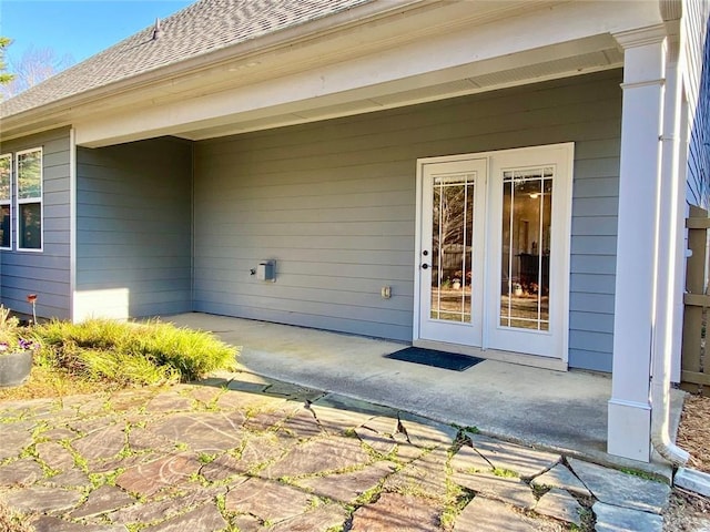 entrance to property featuring a patio area and a shingled roof