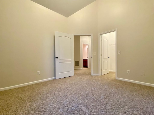 unfurnished bedroom featuring baseboards, high vaulted ceiling, and carpet flooring