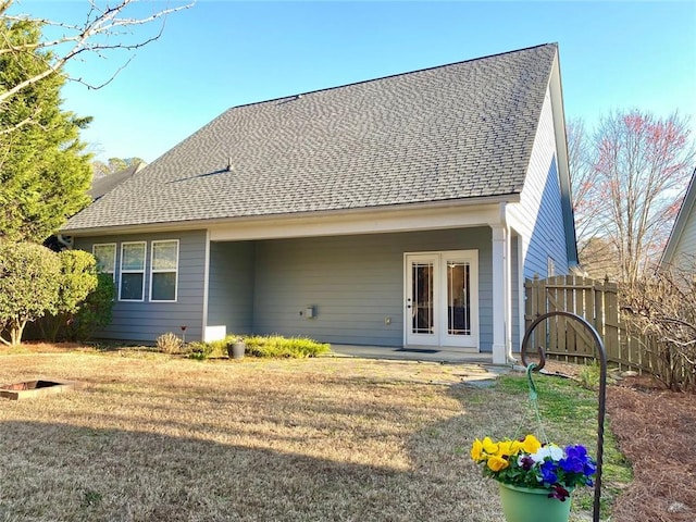 back of property with french doors, fence, a lawn, and roof with shingles