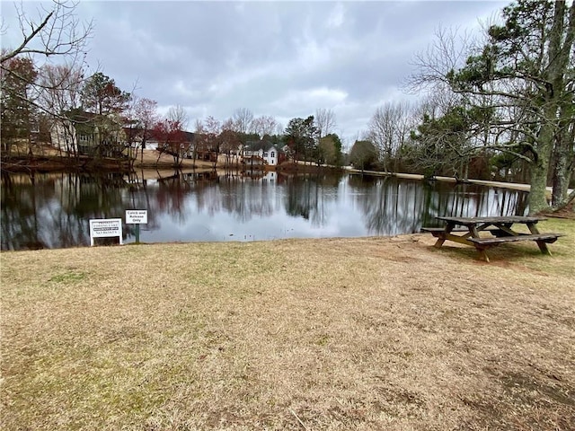 view of dock with a yard and a water view