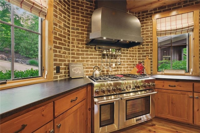 147 Lake Watch Pt, Cleveland, GA 30528 - kitchen with range with two ovens, wall chimney exhaust hood, brown cabinetry, dark countertops, and light wood finished floors