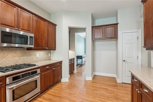 5882 Riverstone Cir Unit 15, Atlanta, GA 30339 - kitchen with stainless steel appliances, light wood-type flooring, tasteful backsplash, light stone countertops, and baseboards