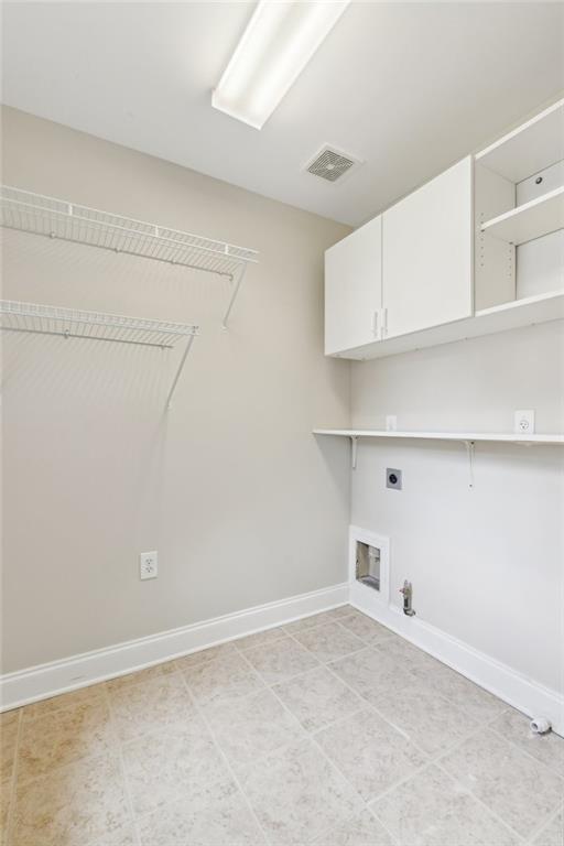 5882 Riverstone Cir Unit 15, Atlanta, GA 30339 - clothes washing area featuring gas dryer hookup, electric dryer hookup, cabinet space, baseboards, and light tile patterned floors