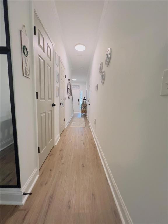 hall with ornamental molding and light hardwood / wood-style flooring