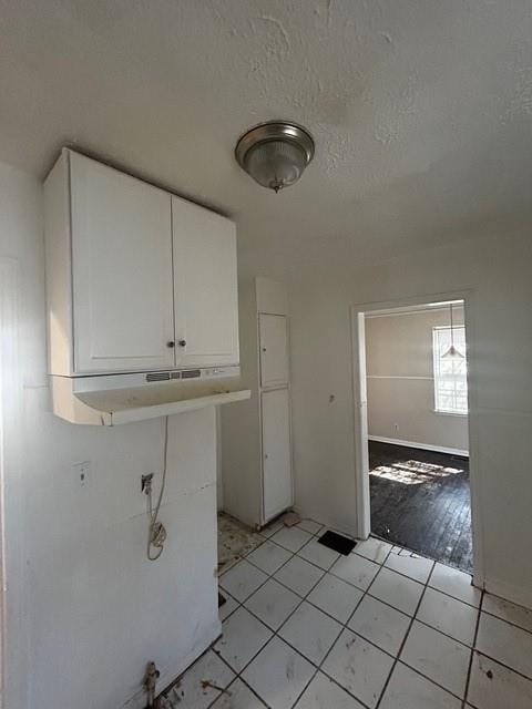 laundry area featuring light tile patterned floors and a textured ceiling