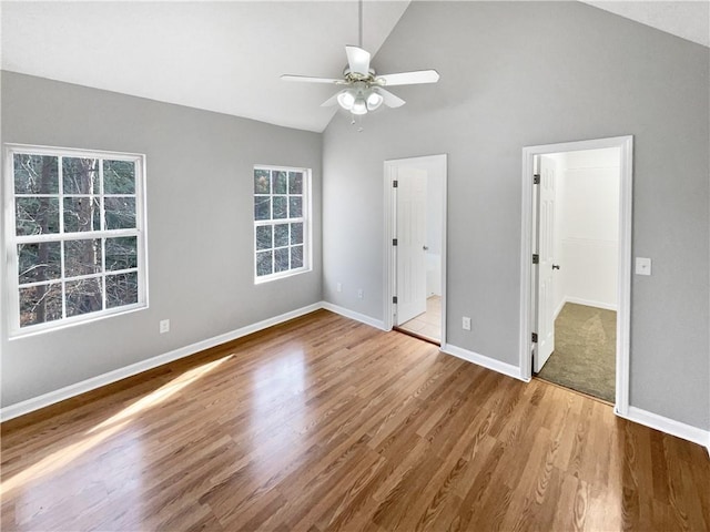 unfurnished bedroom featuring ceiling fan, a spacious closet, high vaulted ceiling, and light hardwood / wood-style flooring