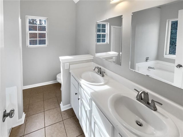 bathroom featuring vanity, a washtub, tile patterned floors, and toilet