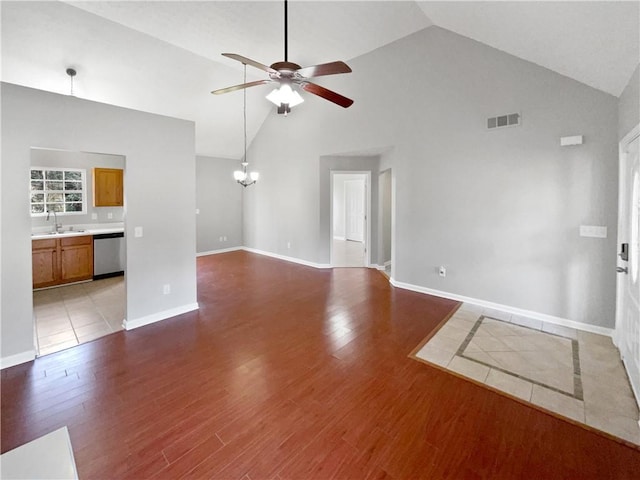 unfurnished living room featuring ceiling fan with notable chandelier, high vaulted ceiling, wood-type flooring, and sink