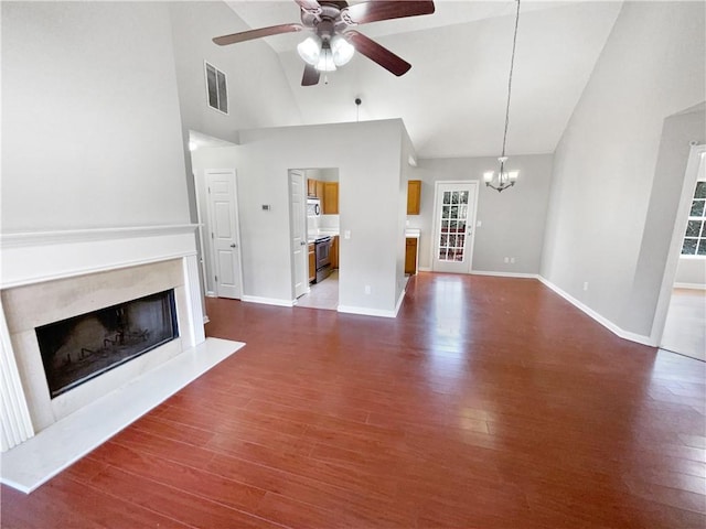 unfurnished living room with high vaulted ceiling, dark hardwood / wood-style floors, ceiling fan with notable chandelier, and a high end fireplace