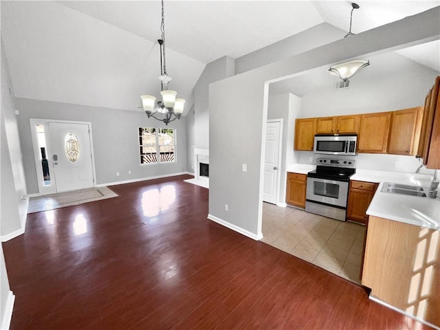 kitchen featuring vaulted ceiling, appliances with stainless steel finishes, decorative light fixtures, sink, and a notable chandelier