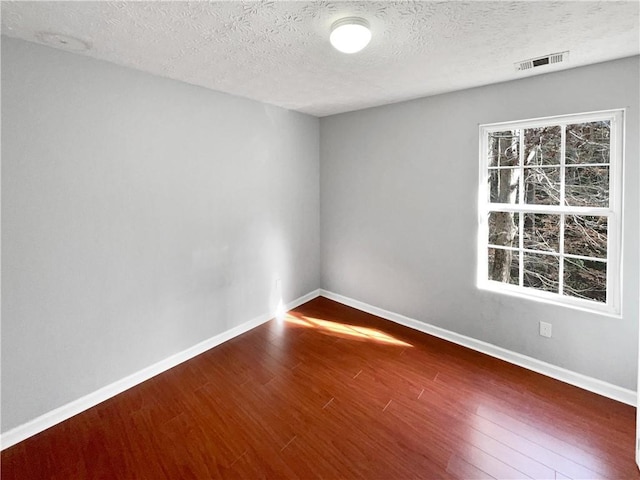 empty room featuring hardwood / wood-style flooring and a textured ceiling