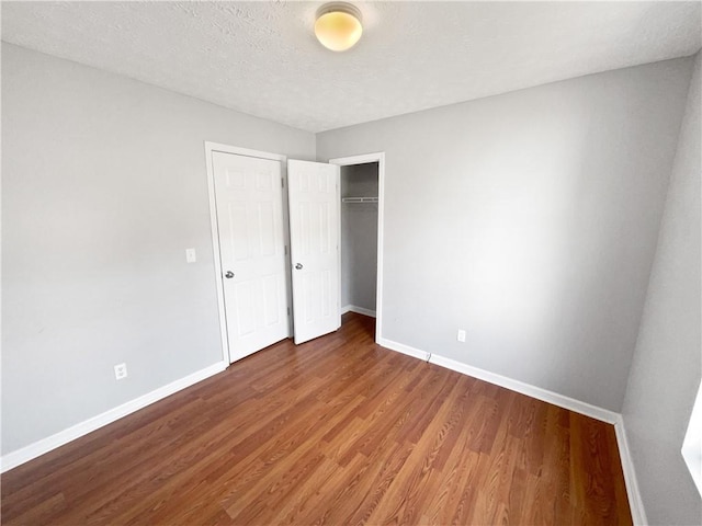 unfurnished bedroom with dark hardwood / wood-style flooring, a closet, and a textured ceiling