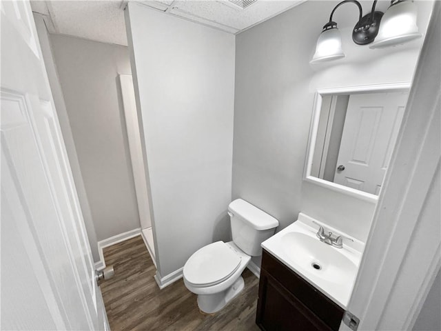 bathroom with vanity, hardwood / wood-style floors, a paneled ceiling, and toilet