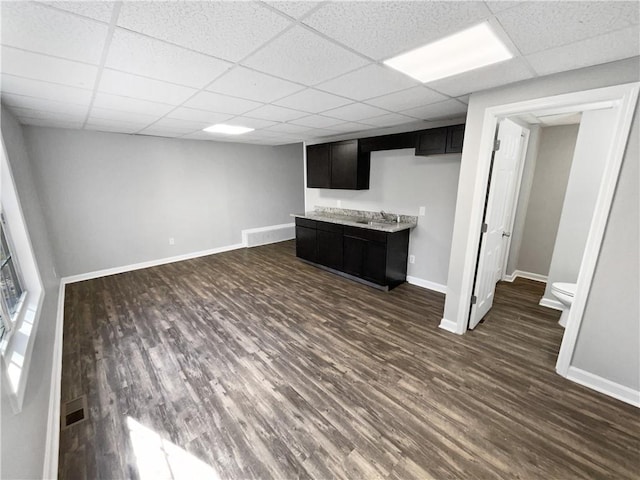 basement featuring a paneled ceiling, dark hardwood / wood-style floors, and sink