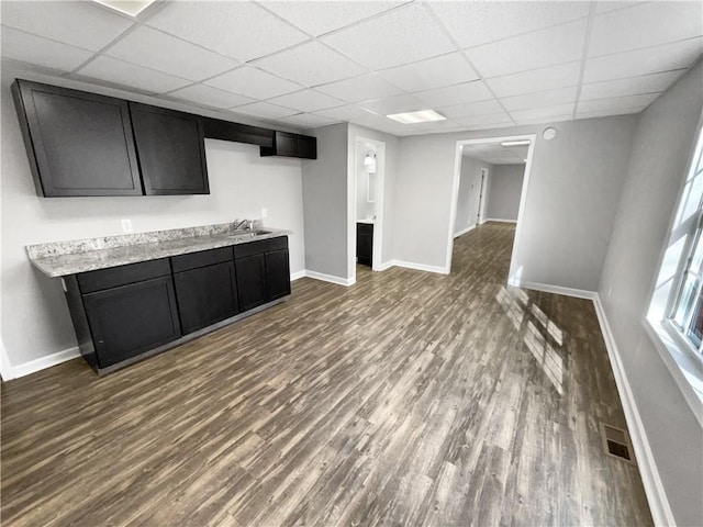 interior space featuring sink, a drop ceiling, and dark hardwood / wood-style floors