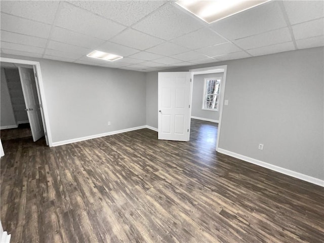 basement featuring dark wood-type flooring and a paneled ceiling