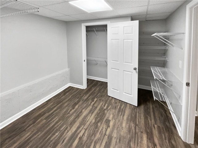 unfurnished bedroom featuring dark wood-type flooring, a closet, and a paneled ceiling