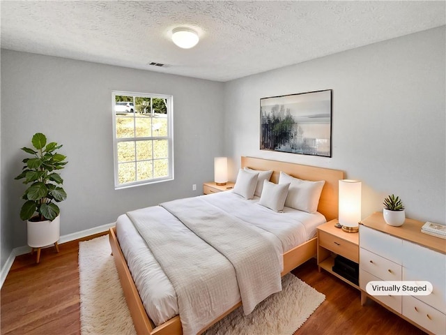 bedroom featuring dark hardwood / wood-style flooring and a textured ceiling