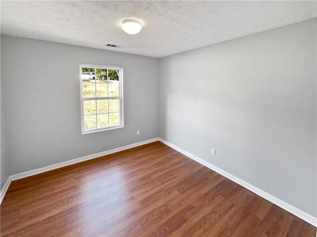 unfurnished room featuring dark hardwood / wood-style flooring and a textured ceiling