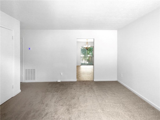 empty room with an inviting chandelier and carpet flooring