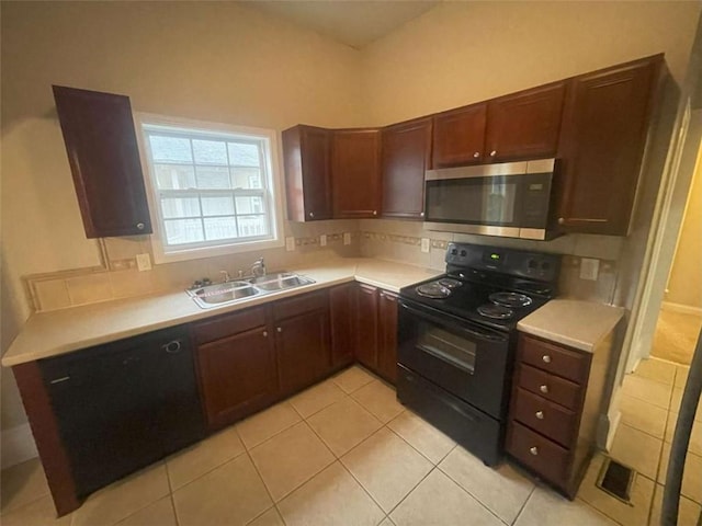 kitchen featuring tasteful backsplash, light tile patterned flooring, black electric range oven, and sink