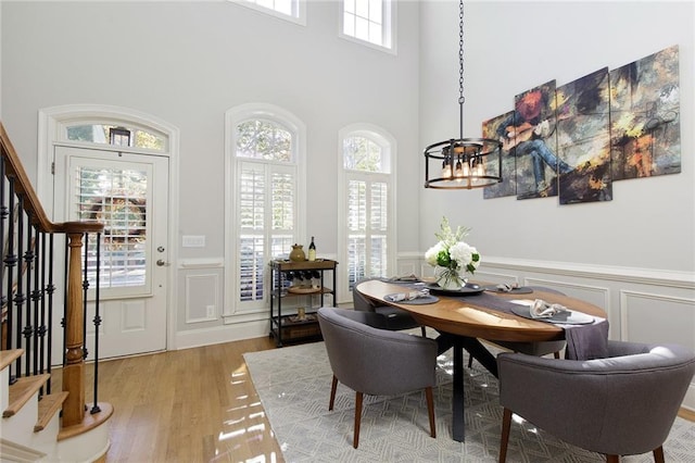 dining room with a chandelier, plenty of natural light, a towering ceiling, and hardwood / wood-style floors