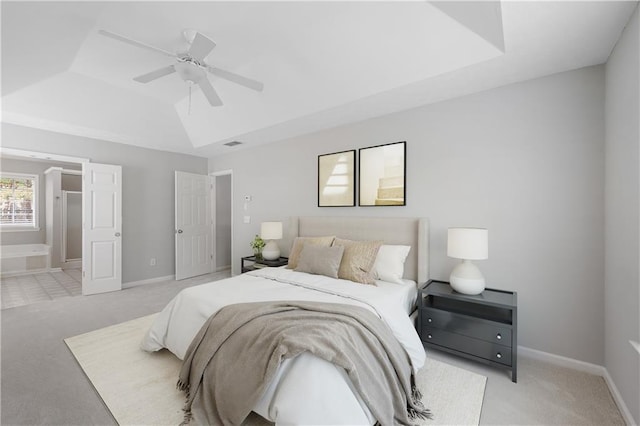 bedroom with a raised ceiling, ceiling fan, and light colored carpet