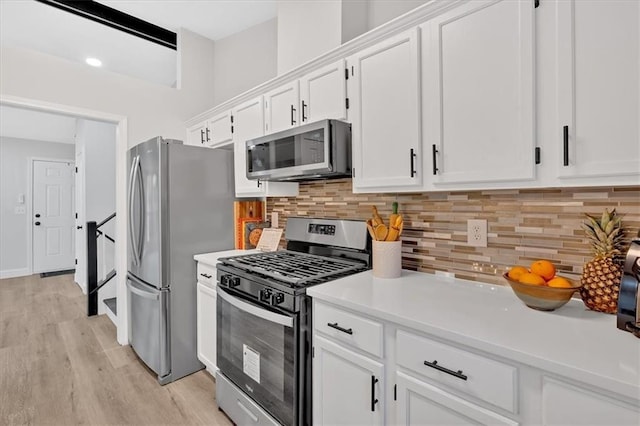 kitchen with stainless steel appliances, white cabinets, decorative backsplash, and light countertops