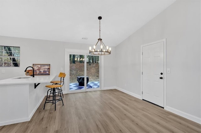 unfurnished dining area with lofted ceiling, a healthy amount of sunlight, light wood finished floors, and a sink