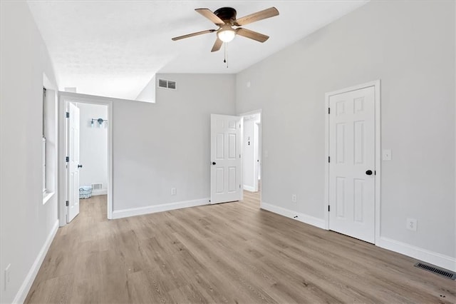 unfurnished bedroom with vaulted ceiling, light wood-style floors, visible vents, and baseboards