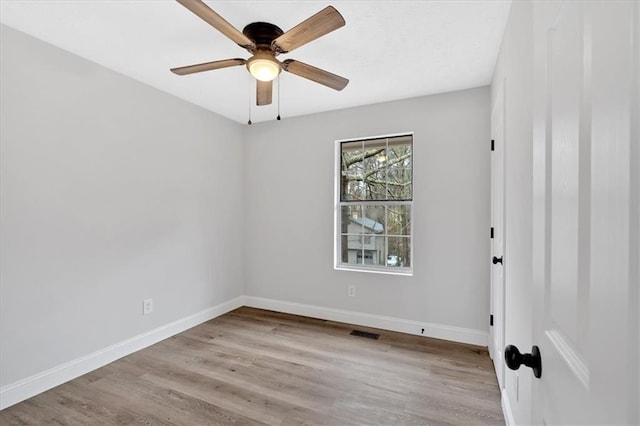 spare room featuring ceiling fan, wood finished floors, visible vents, and baseboards