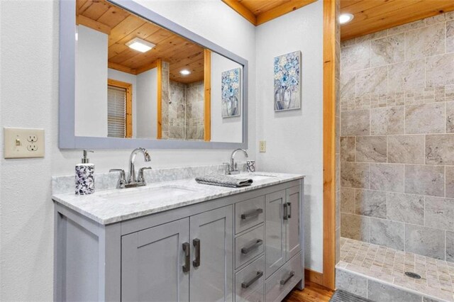 bathroom with vanity, a tile shower, hardwood / wood-style flooring, and wooden ceiling