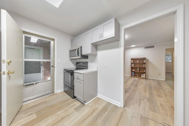 1111 Clairemont Ave Unit N3, Decatur, GA 30030 - kitchen with black range with electric cooktop, stainless steel microwave, light wood-style floors, light countertops, and baseboards