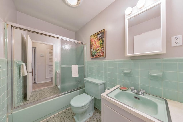 1111 Clairemont Ave Unit N3, Decatur, GA 30030 - bathroom featuring combined bath / shower with glass door, vanity, toilet, tile walls, and a wainscoted wall