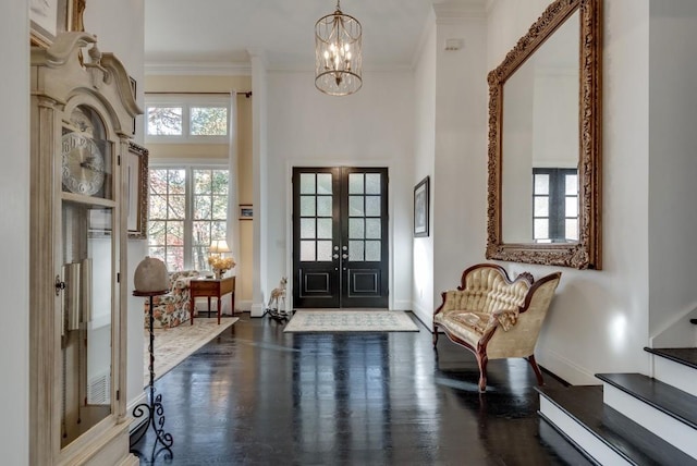 entryway with french doors, a high ceiling, dark hardwood / wood-style flooring, a notable chandelier, and crown molding