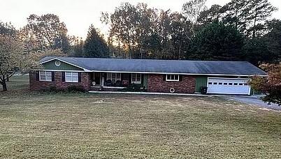 ranch-style house with an attached garage, driveway, and a front yard
